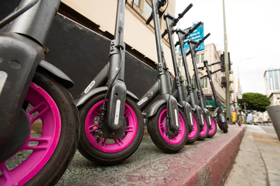 Low close-up shot of black and pink Lyft e-scooters lined up on downtown Los Angeles sidewalk